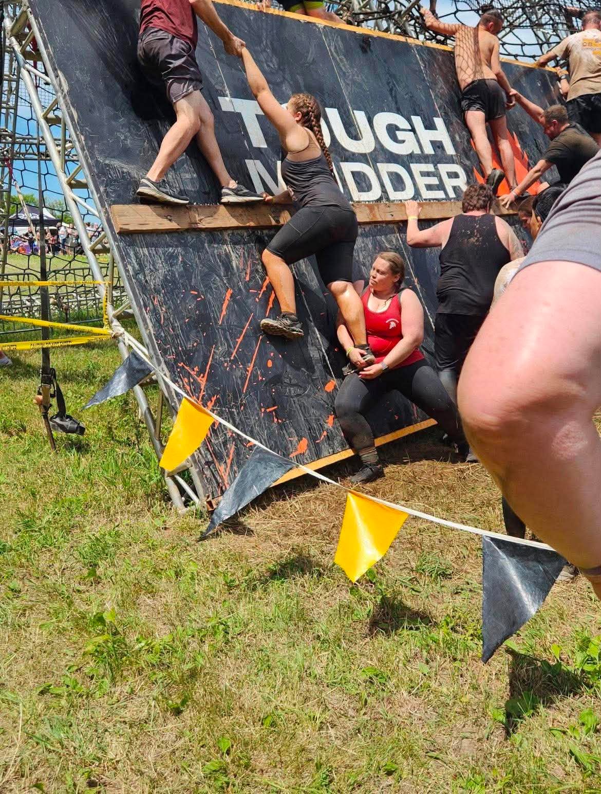 Zoe climbing an obstacle wall at a Tough Mudder race