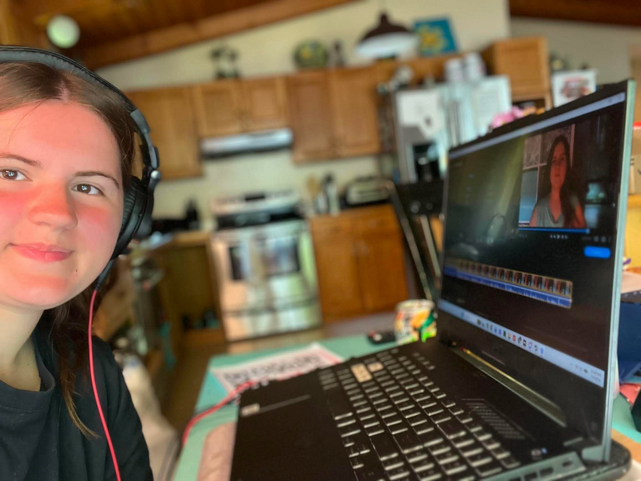 Zoe wearing headphones while editing videos on her laptop